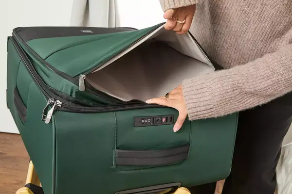 A person holds open the pocket on the Antler Soft Stripe Lightest Large Luggage