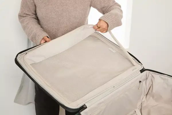 A person unzips the pocket inside the Antler Soft Stripe Lightest Large Luggage