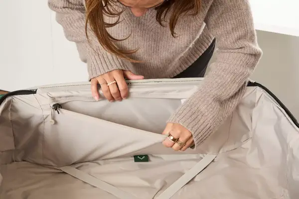 A person holds open a pocket on the Antler Soft Stripe Lightest Large Luggage