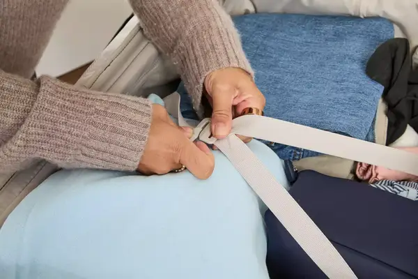 A person secures the straps on the Antler Soft Stripe Lightest Large Luggage