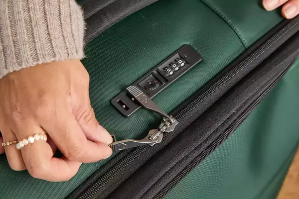 A person unzips the Antler Soft Stripe Lightest Large Luggage