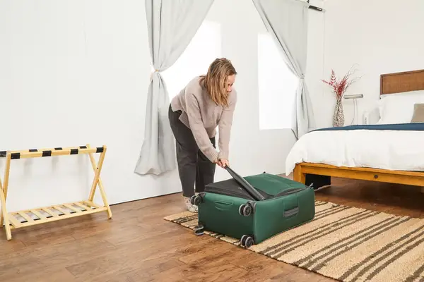 A person hits the Antler Soft Stripe Lightest Large Luggage with a baseball bat