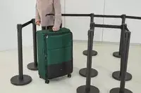 A person wheels the Antler Soft Stripe Lightest Large Luggage around an airport line