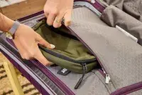 A person places a travel pack into the pocket of the Samsonite 21 Inch Freeform Hardside Expandable Carry-on Spinner