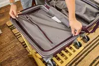 A person unzips a pocket on the Samsonite 21 Inch Freeform Hardside Expandable Carry-on Spinner