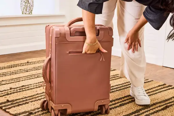 A person reaches inside the back pocket on the Dagne Dover Smaller Seattle Carry-on Luggage 20.5 Inches