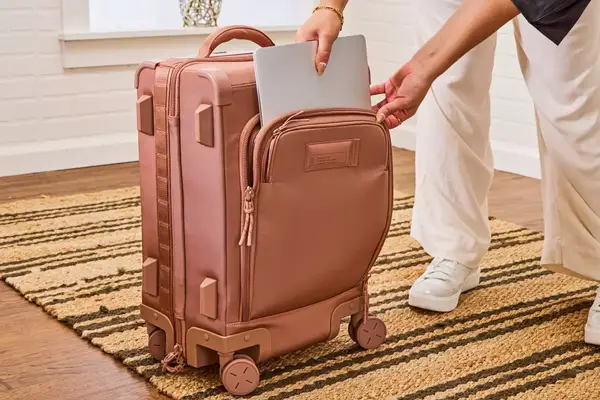 A person places a laptop into the front pocket of the Dagne Dover Smaller Seattle Carry-on Luggage 20.5 Inches