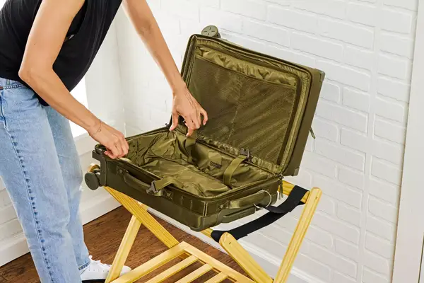 A person touching an empty Dagne Doverr Seattle Carry On Rolling Luggage 20.5