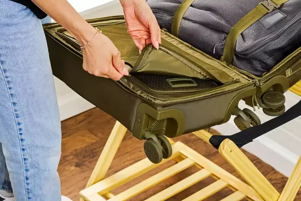 A person unzipping a compartment in the Dagne Doverr Seattle Carry On Rolling Luggage 20.5