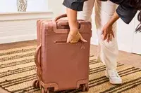 A person reaches inside the back pocket on the Dagne Dover Smaller Seattle Carry-on Luggage 20.5 Inches