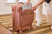 A person places a laptop into the front pocket of the Dagne Dover Smaller Seattle Carry-on Luggage 20.5 Inches