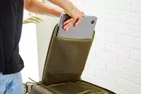 A person placing a laptop inside of a compartment in the Dagne Doverr Seattle Carry On Rolling Luggage 20.5