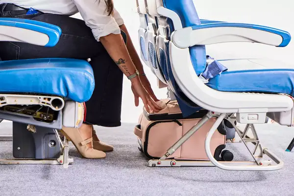 A person stowing the Calpak Luka Soft-sided Mini Carry-on Luggage under the seat of an airplane