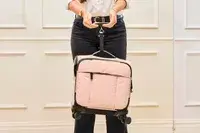 A person using a handheld scale to weigh the Calpak Luka Soft-sided Mini Carry-on Luggage