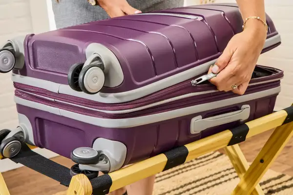 Person weighing the Samsonite Winfield 2 Hardside Luggage With Spinner Wheels while another watches