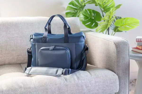 The July Carry All Weekender placed on a suitcase handle