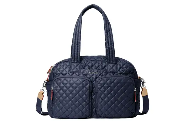 A person walking while holding the Longchamp Le Pliage Expandable Travel Bag in their hand