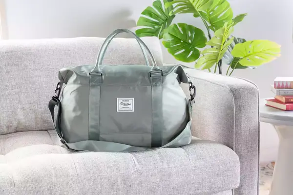 A person opening the zipper to the Longchamp Le Pliage Expandable Travel Bag