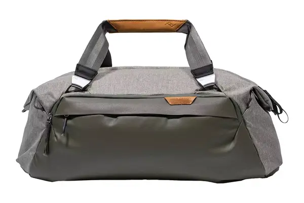 A person sitting while holding the handles of the Longchamp Le Pliage Expandable Travel Bag in their hand