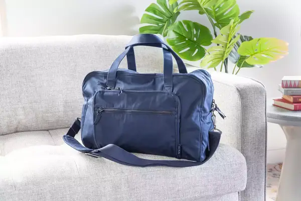A hand putting a shoe into the Calpak Luka Duffel Bag