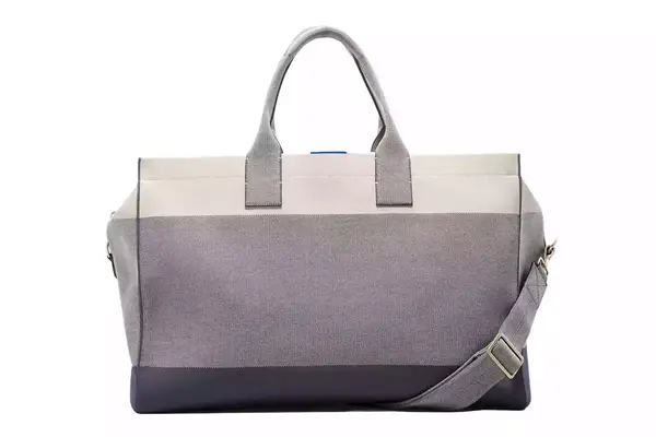 A hand putting a shoe into the Calpak Luka Duffel Bag