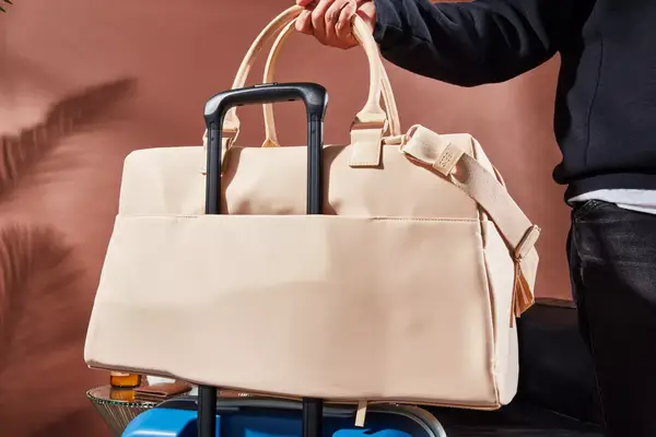 A person placing the Béis The Commuter Duffle on a suitcase handle