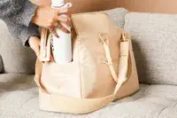 A person placing a water bottle on the Béis The Commuter Duffle