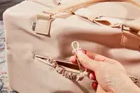 Hand holding a clip from the Béis The Commuter Duffle