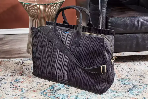 The Rothyâs The Weekender bag on a rug next to furniture