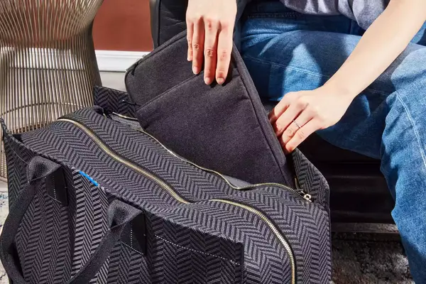 A person placing an item into the Rothyâs The Weekender