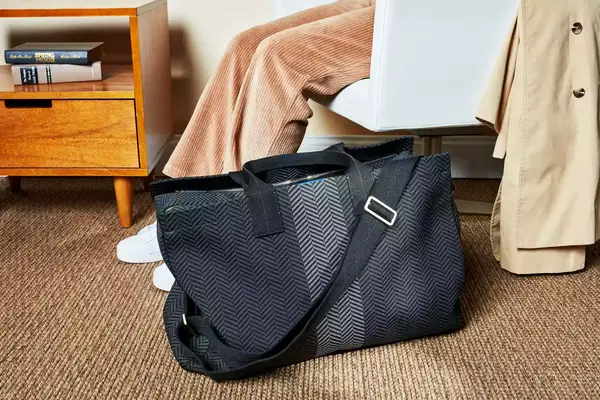 The Rothyâs The Weekender on a carpet next to a sitting person