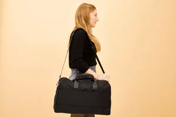 Person unpacking Away The Large Everywhere Bag with another person sitting on bed