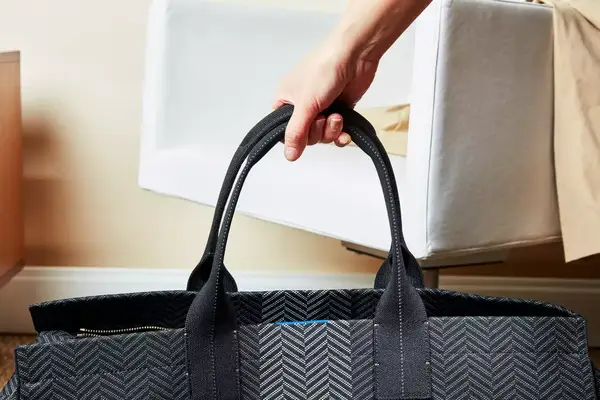 A hand holding the Rothyâs The Weekender handles