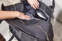 Two hands opening the Rothyâs The Weekender