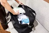 A person putting item into the Rothyâs The Weekender on a couch