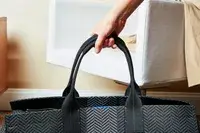 A hand holding the Rothyâs The Weekender handles