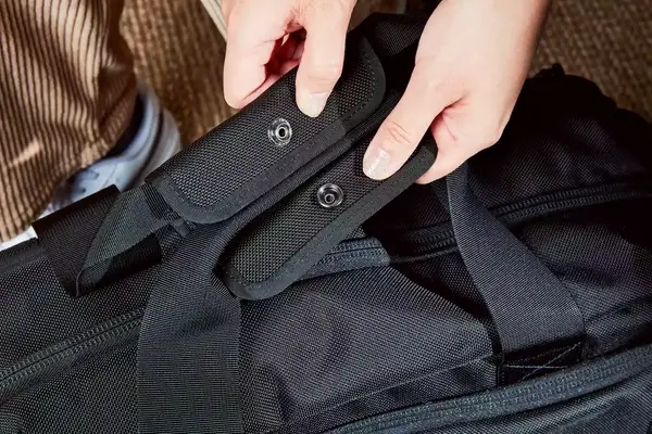 A person unsnapping the handles of the Aer Travel Weekender