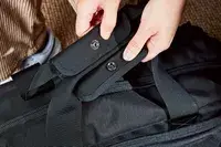 A person unsnapping the handles of the Aer Travel Weekender