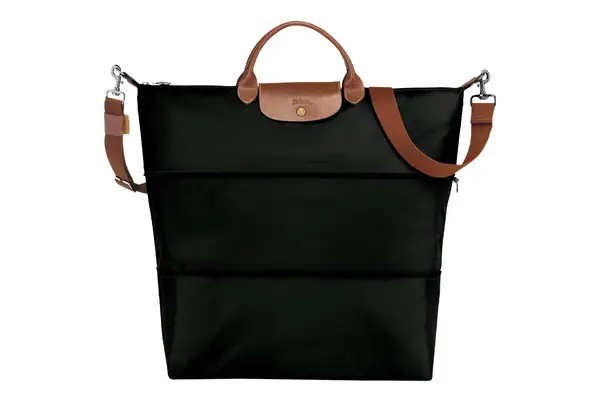 A person packing shoes into the July Carry All Weekender