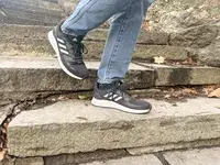 Person walking down stairs wearing gray Adidas Men