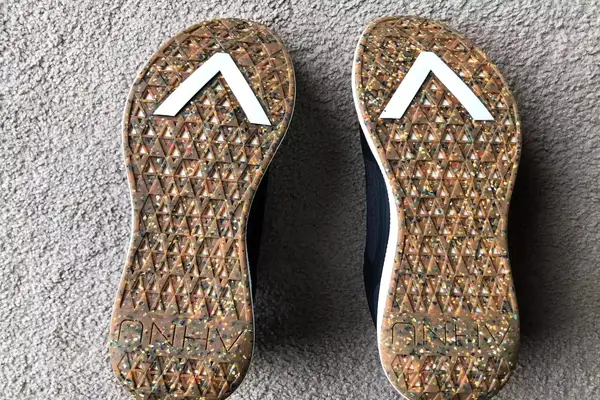 The bottom of two AHNU Sequence 1 sneakers on carpet