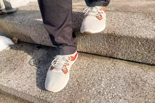 Person walking on concrete stairs wearing Olukai Mio Lī sneakers