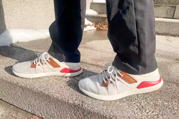 Person walking on concrete stairs wearing Olukai Mio Lī sneakers