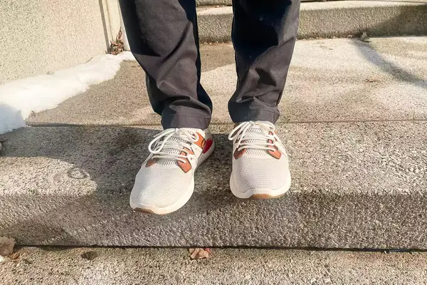 Person walking on concrete stairs wearing Olukai Mio Lī sneakers
