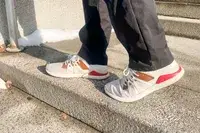 Person walking on concrete stairs wearing Olukai Mio Lī sneakers