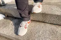 Person walking on concrete stairs wearing Olukai Mio Lī sneakers