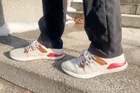 Person walking on concrete stairs wearing Olukai Mio Lī sneakers