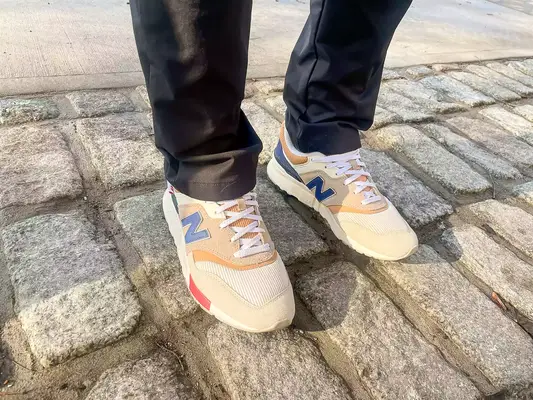 person wearing New Balance 997H V1 Sneakers on a brick floor