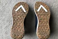 The bottom of two AHNU Sequence 1 sneakers on carpet