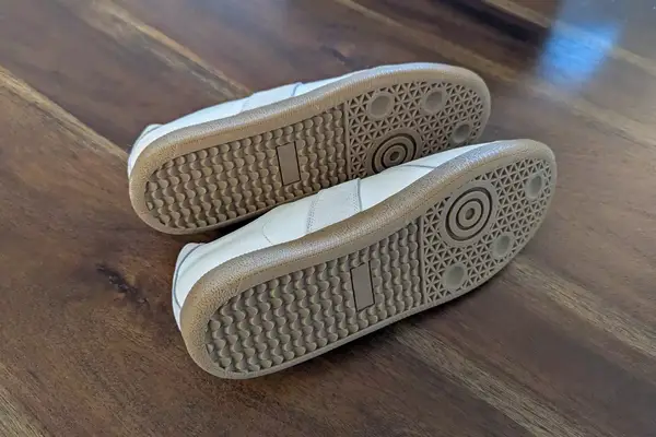 Two Beckett Simonon Leather and Suede Morgen Trainers posed on their side to show the shoes bottom on wood